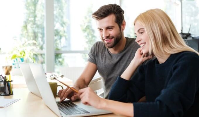 mężczyzna i kobieta siedzący przed laptopem